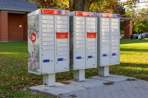 A Canada Post community mailbox unit standing on a grass verge in a residential street