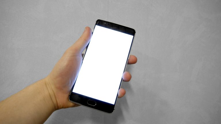 A hand holding a smartphone with a blank screen