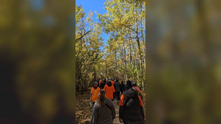 People wearing orange shirts walking along a wooded trail on Orange Shirt Day