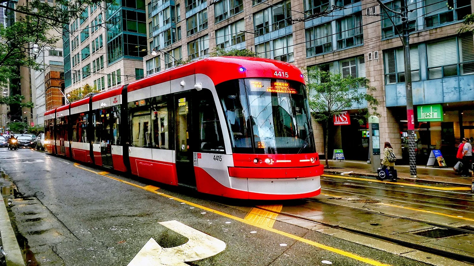 A red and white TTC Flexity streetcar on a Toronto street