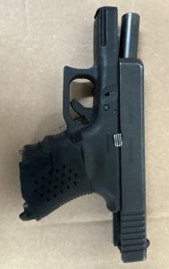A black semi-automatic handgun with an extended magazine, photographed on a flat surface