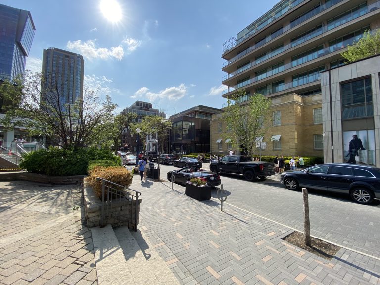 Shops and low-rise buildings lining Yorkville Avenue in Toronto on a clear day.